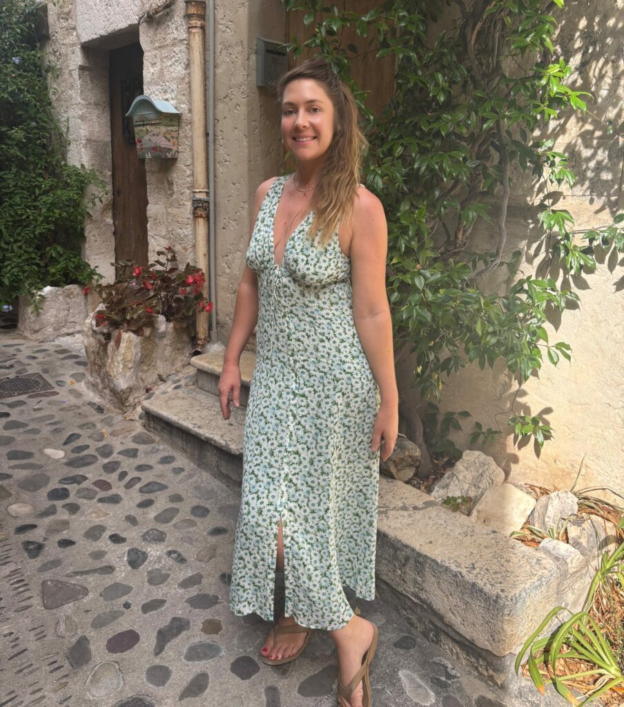 Juliette in a long airy dress by an old stone house.