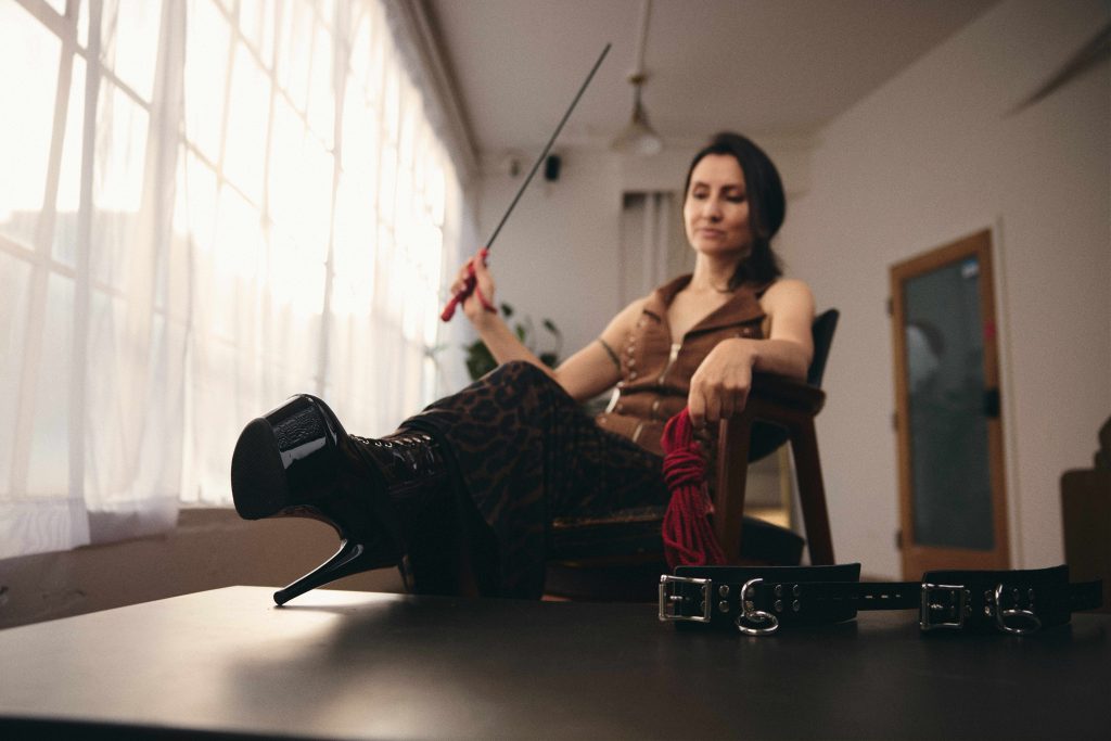 Kalika with her high-heeled shoes on the table next to a belt.