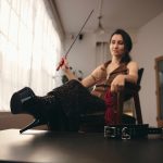 Kalika with her high-heeled shoes on the table next to a belt.