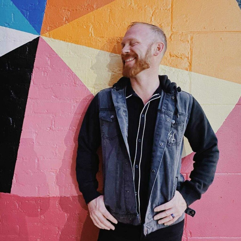 Smiling Kinsey in front of a colorful wall.