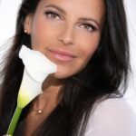 Close-up of Skyler holding a white flower next ot her face.