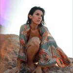 Squatting on the rocks. Katarsis is wearing a colorful oriental robe.