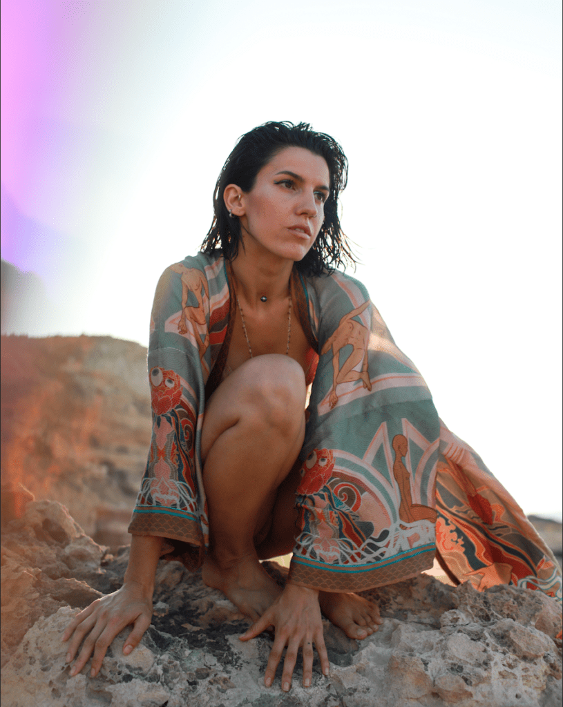 Squatting on the rocks. Katarsis is wearing a colorful oriental robe.
