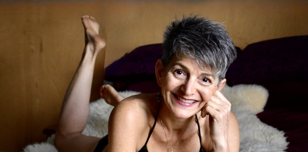 Liz Dake on bed with a big smile.