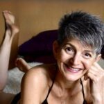 Liz Dake on bed with a big smile.
