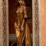 Beautiful patterned doorway surronding Ruby Lovelight who is wearing and elegant long golden dress.