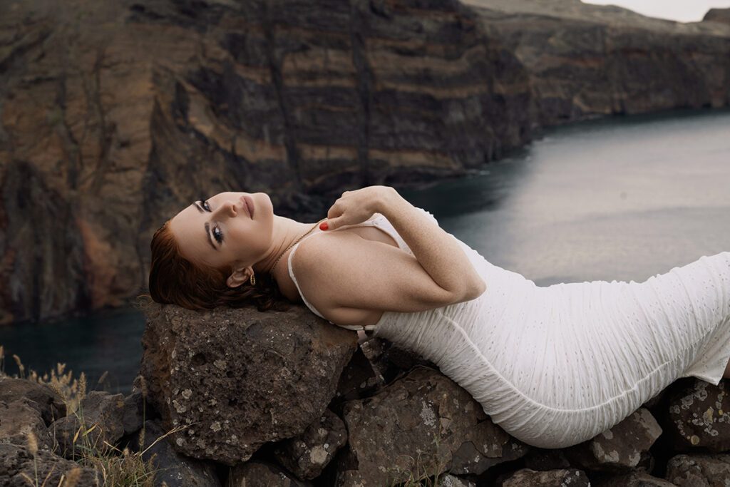 Jo on the rocks in a white dress.