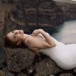 Jo on the rocks in a white dress.