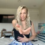 Kat holding one hand on her belly and reaching out with the other.