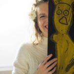 Peeking out from behind an art piece. Half of Kat's big smile is hidden.