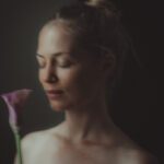 Profile shot of Imaya with her eyes closed and holding a flower in front of her.