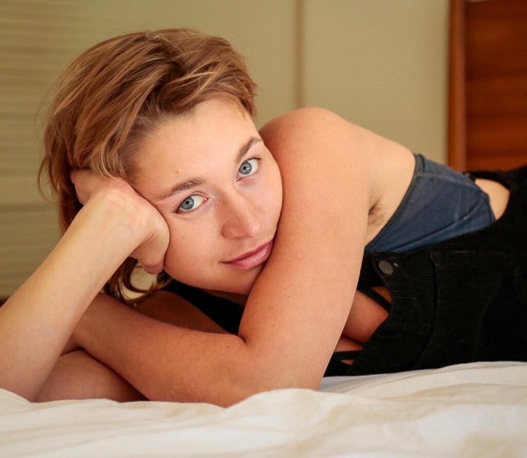 Jaquelin Laurent lying on bed with blue eyes looking towards the camera.
