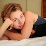 Jaquelin Laurent lying on bed with blue eyes looking towards the camera.