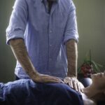 Female client on the table. Eric is placing his hands on her chest.
