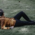 Eric lying down on the grass in orange shirt.