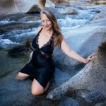 Veritie in a black swimdress by a wild river.
