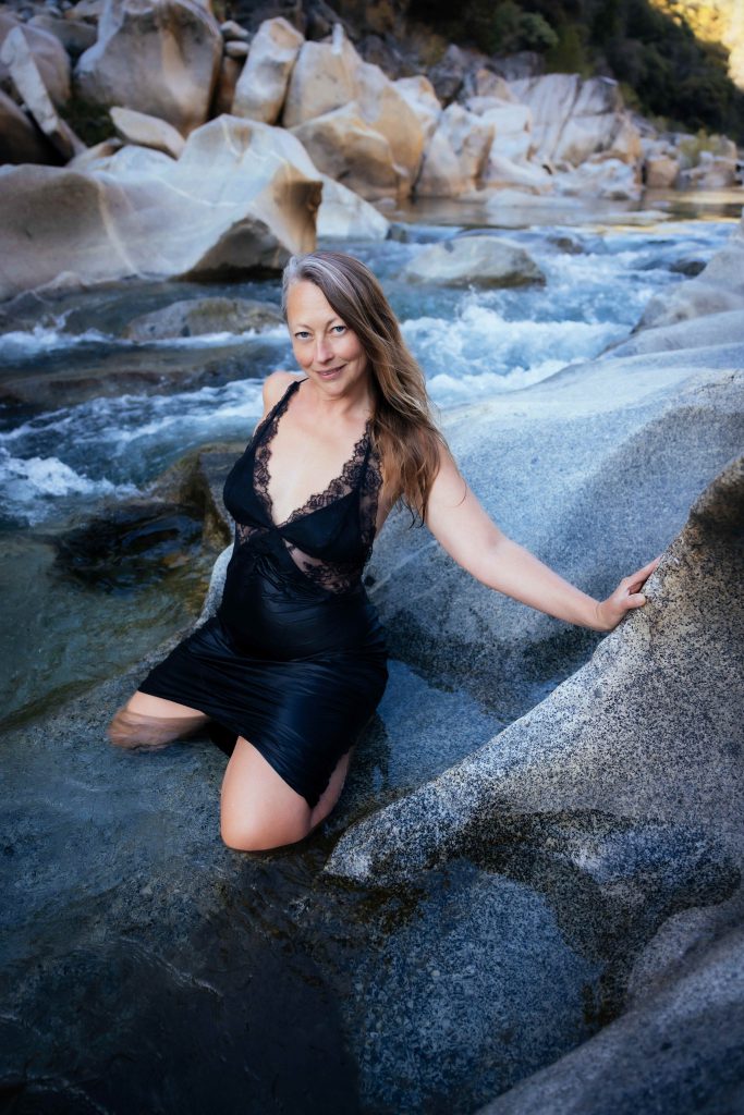 Veritie in a black swimdress by a wild river.