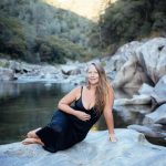 Picturesque wild riverside with Veritie sitting on a big rock.