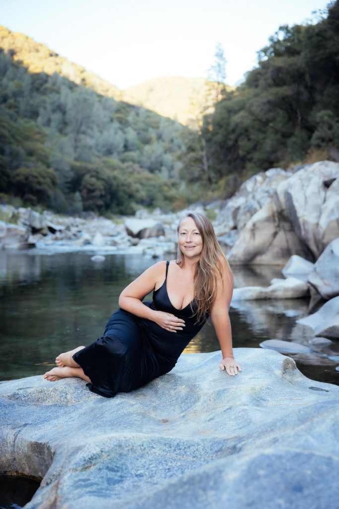 Picturesque wild riverside with Veritie sitting on a big rock.