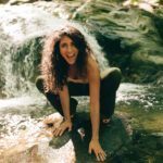 Wild smily on her face, Ariadne is squatting on a rock in a wild river.