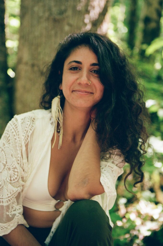 Ariadne with a warm smile in front of a tree.