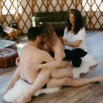 A couple sitting on the floor and embracing. Aiua in the back.