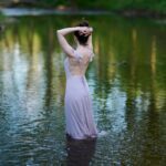 Standing in a lake wearing a long light-purple dress.