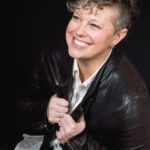 Kel with a big smile in a black leather jacket.