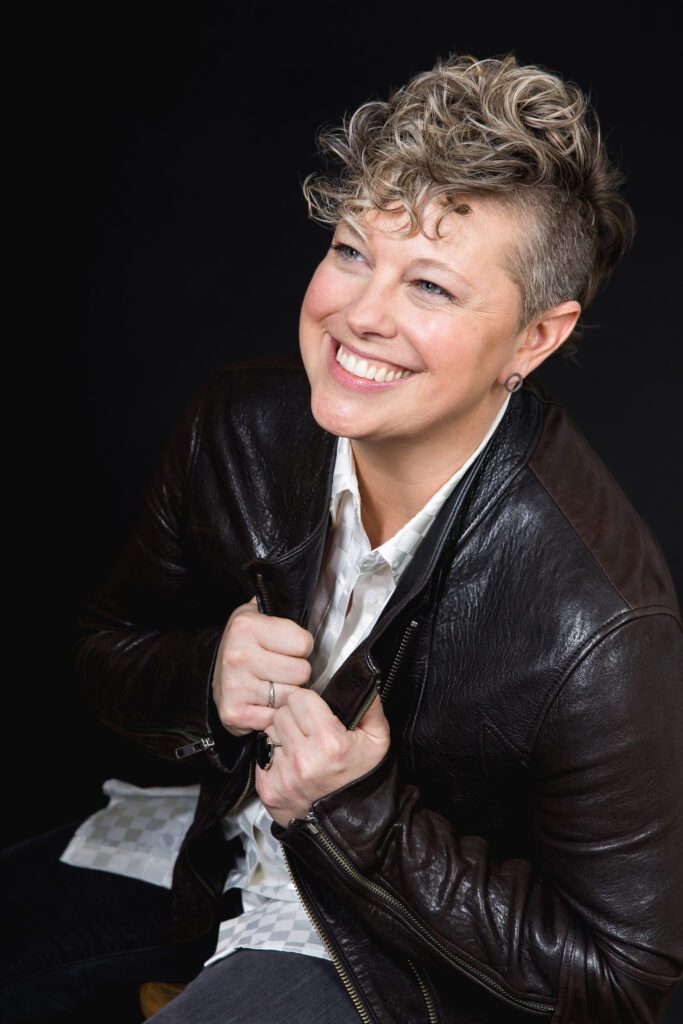 Kel with a big smile in a black leather jacket.