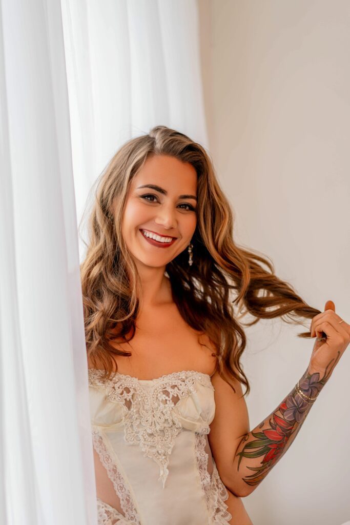 Helena by the window with a big smile in white dress.