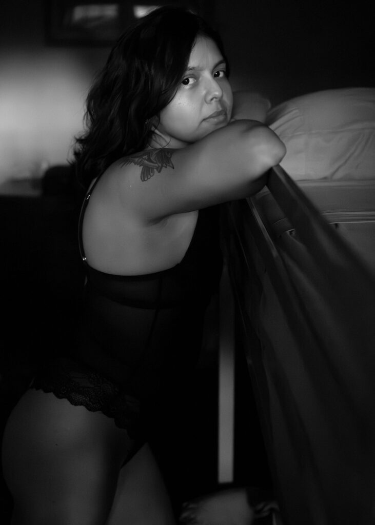 Black&white shot of Amada leaning against a high bed.