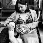 Amada sitting on the stairs with a clients head wrapped in fabric resting on her lap.