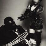 Male client is tied up while wearing a mask. LadyKin doing her work.
