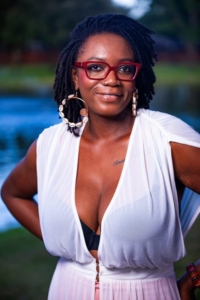 Content Sunmi Vailfyre wearing red-framed glasses smiling to the camera.