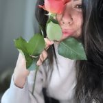 Madison holding a rose in front of her face.
