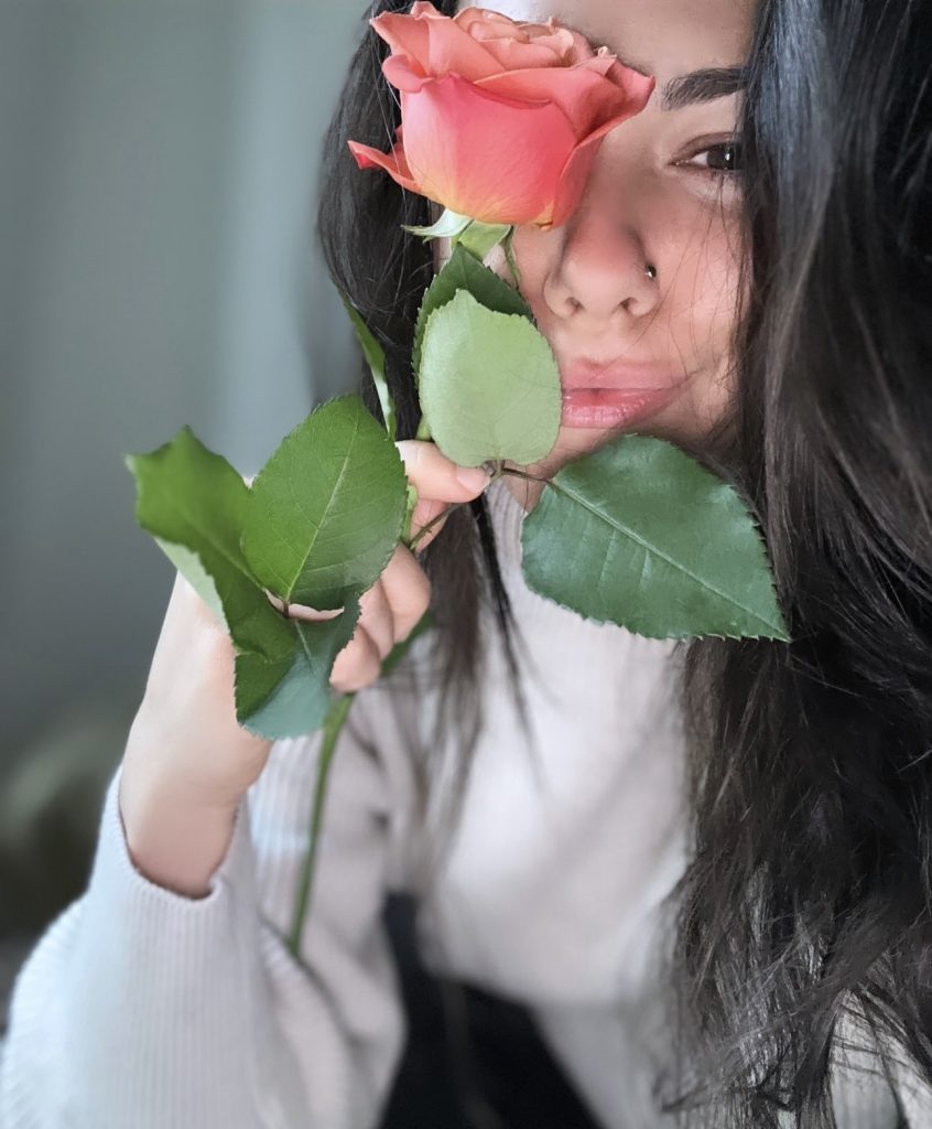 Madison holding a rose in front of her face.