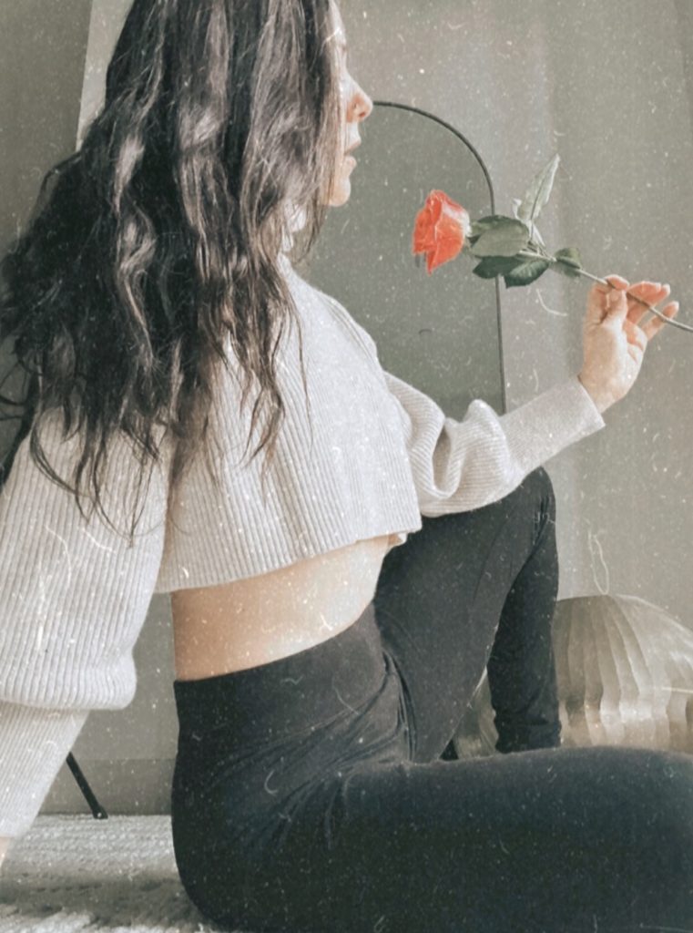 Madison from the side looking at a rose in her hand.