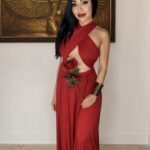 Inanna Magdalena in front of an artpiece in red dress.