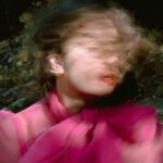 Artistic close-up of Allie's blurry face with red lipstick and pink fluffy shirt.