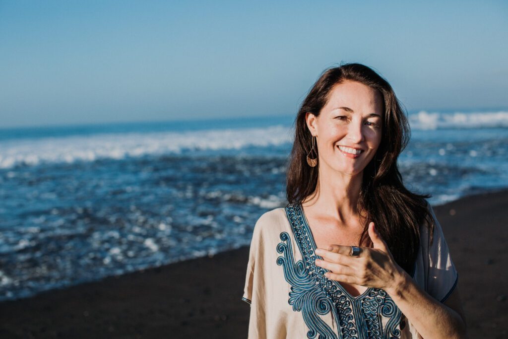 Robyn standing on the seashore with one hand on the chest.
