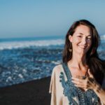 Robyn standing on the seashore with one hand on the chest.