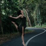 Small country road with Roby Lynn balancing on one leg on the separating line in the middle of the road.