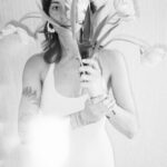 Roman wearing white and holding some flowers and a knife in her hands.