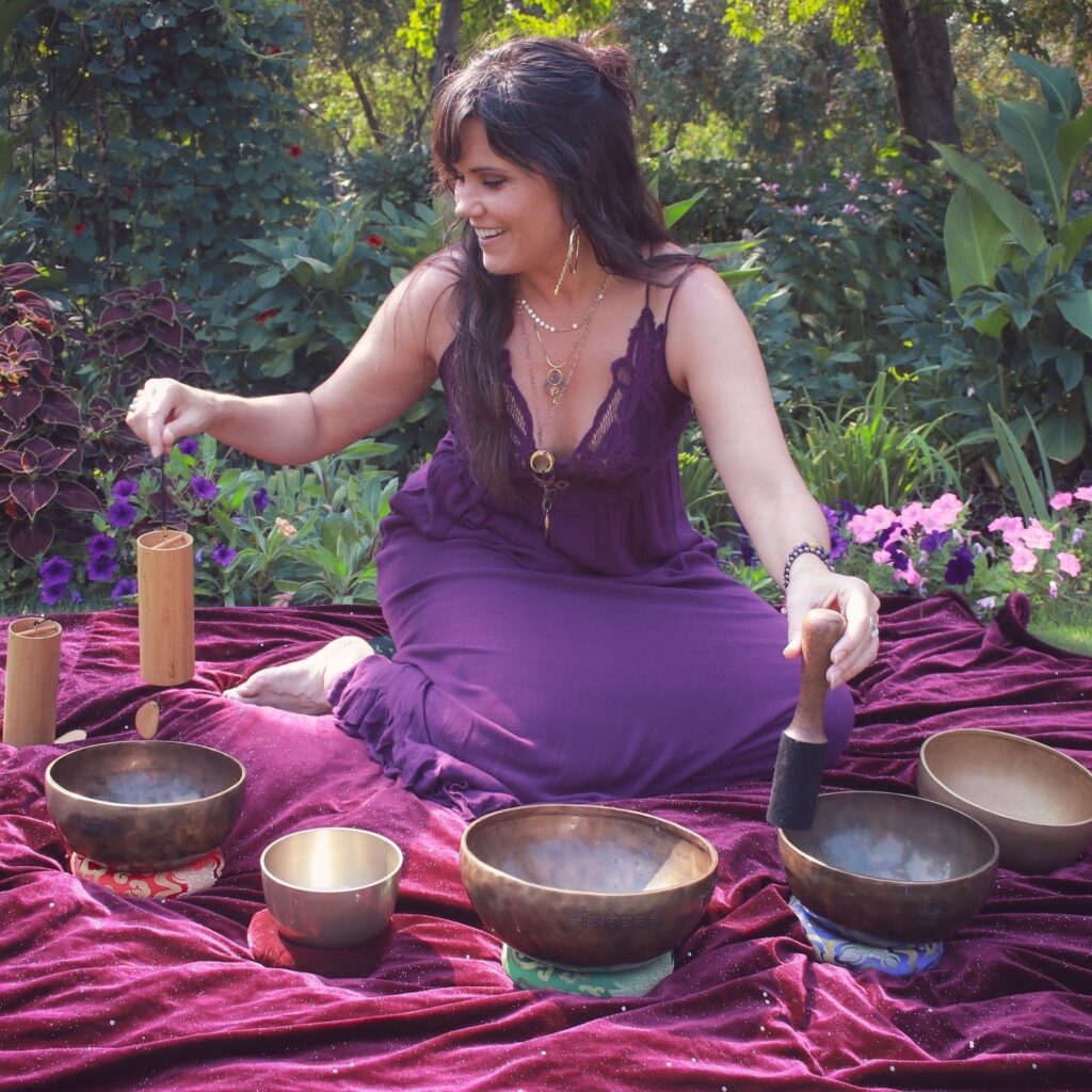 SInging bowls on a purple blanket. Aurora is making sounds with the bowls.