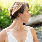 Gaia in a white bra looking to the side.