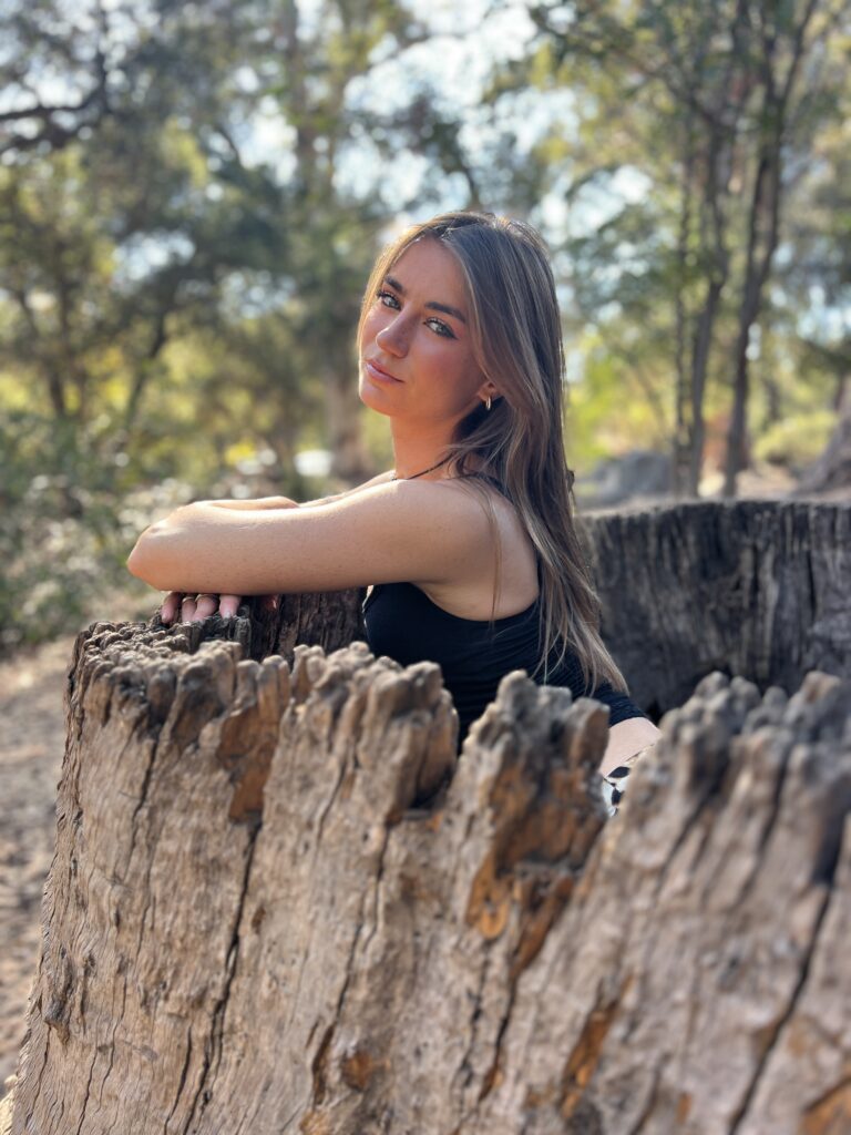 In a tree stump. Sterling looking to the camera with sun on her face.