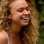 Close up of Gina - curly hair, big smile, eyes closed.