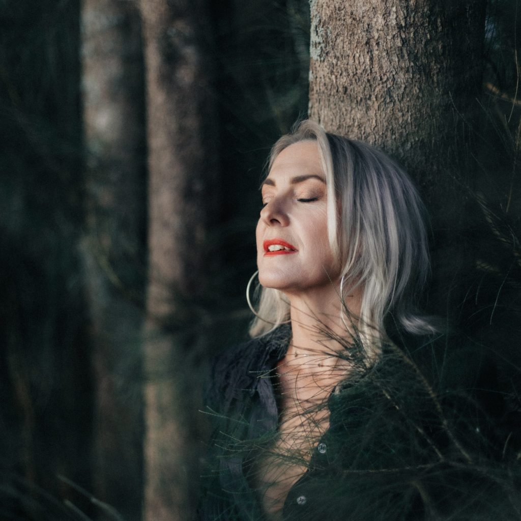 Ellie eyes closed leaning against a tree.