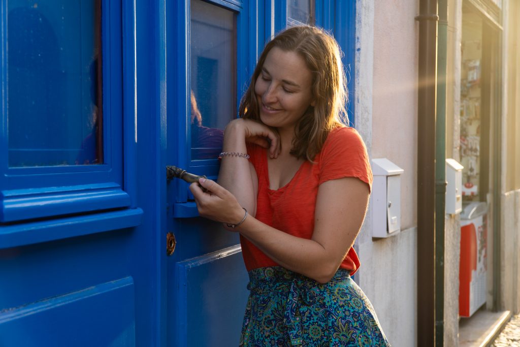 Heather Catherine holding a handle of a blue door.