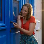 Heather Catherine holding a handle of a blue door.